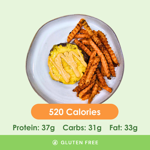 A juicy backyard bison burger topped with melted cheese, served alongside crispy sweet potato fries, with calorie and macronutrient information.