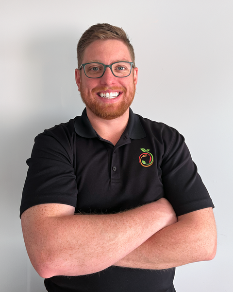 Headshot of a smiling man with glasses, wearing a black Fresh Fit Meals polo.