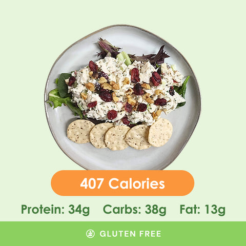 A fresh and flavorful chicken salad, generously studded with dried cranberries and walnuts, served with a side of savory crackers.