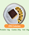 A delicious Fit Snick bar with a chocolate top, served on a plate with a drizzle of caramel, chocolate chips, and chopped nuts.