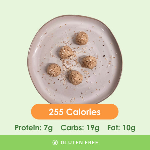 Five delicious, bite-sized peanut butter energy balls, sprinkled with coconut flakes, on a white plate.