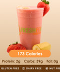 A refreshing pink strawberry banana smoothie in a clear cup, with a whole strawberry and half a banana beside it.