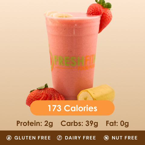 A refreshing pink strawberry banana smoothie in a clear cup, with a whole strawberry and half a banana beside it.